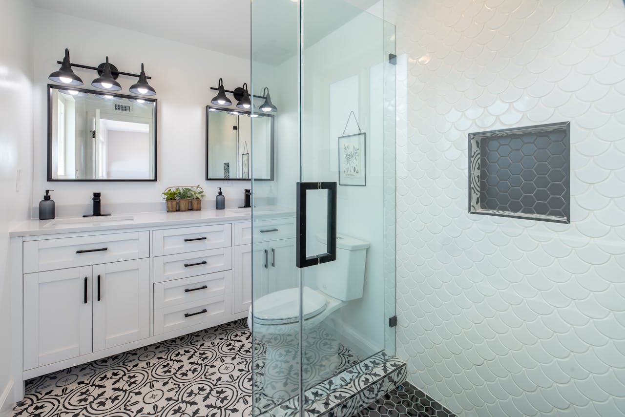 Elegant white bathroom with glass shower and stylish patterned floor.